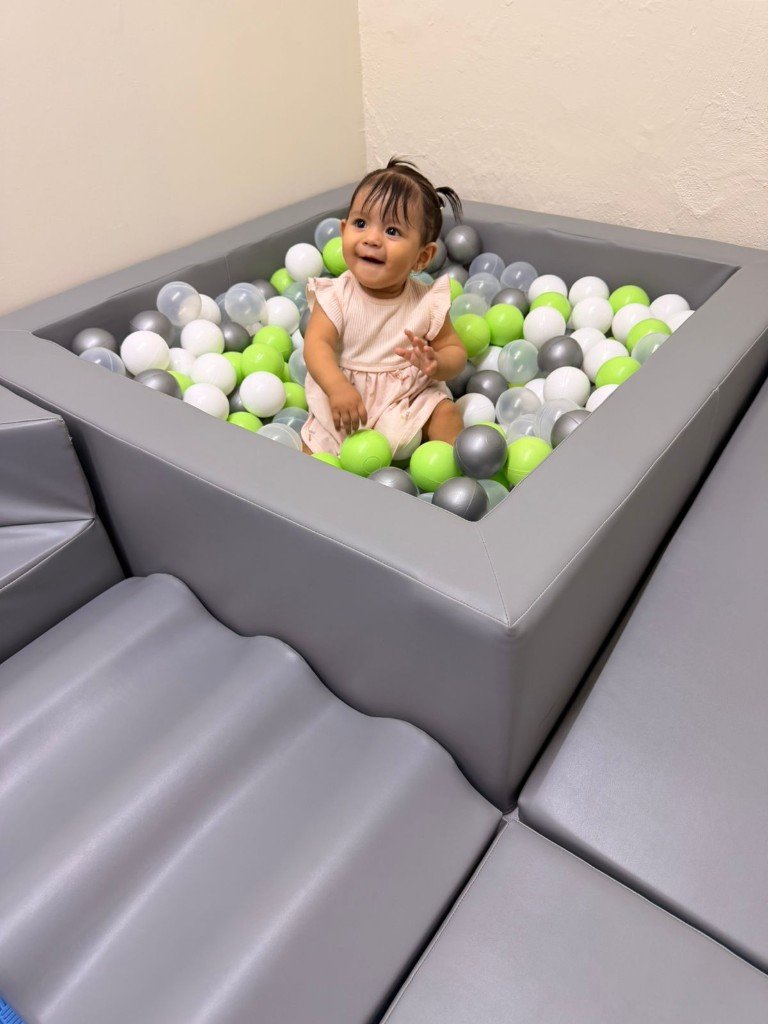 Niña sonriendo en piscina de pelotas durante terapia sensorial en HablaNova Kids